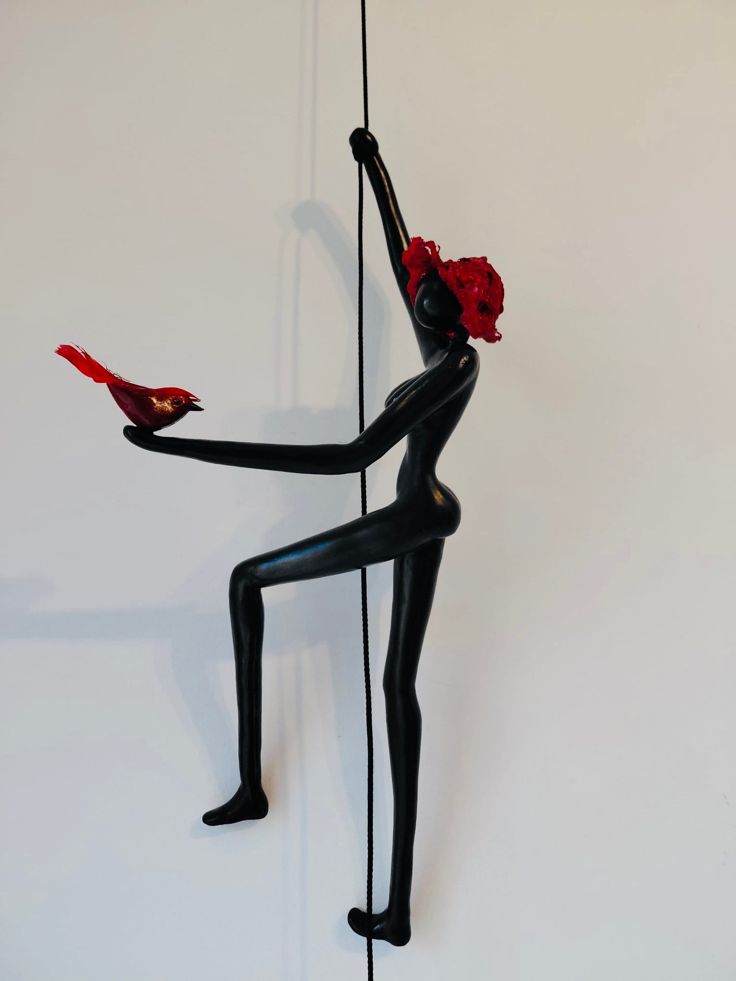 Geveltoeriste met rood hoedje en rood vogeltje aan klimkoord